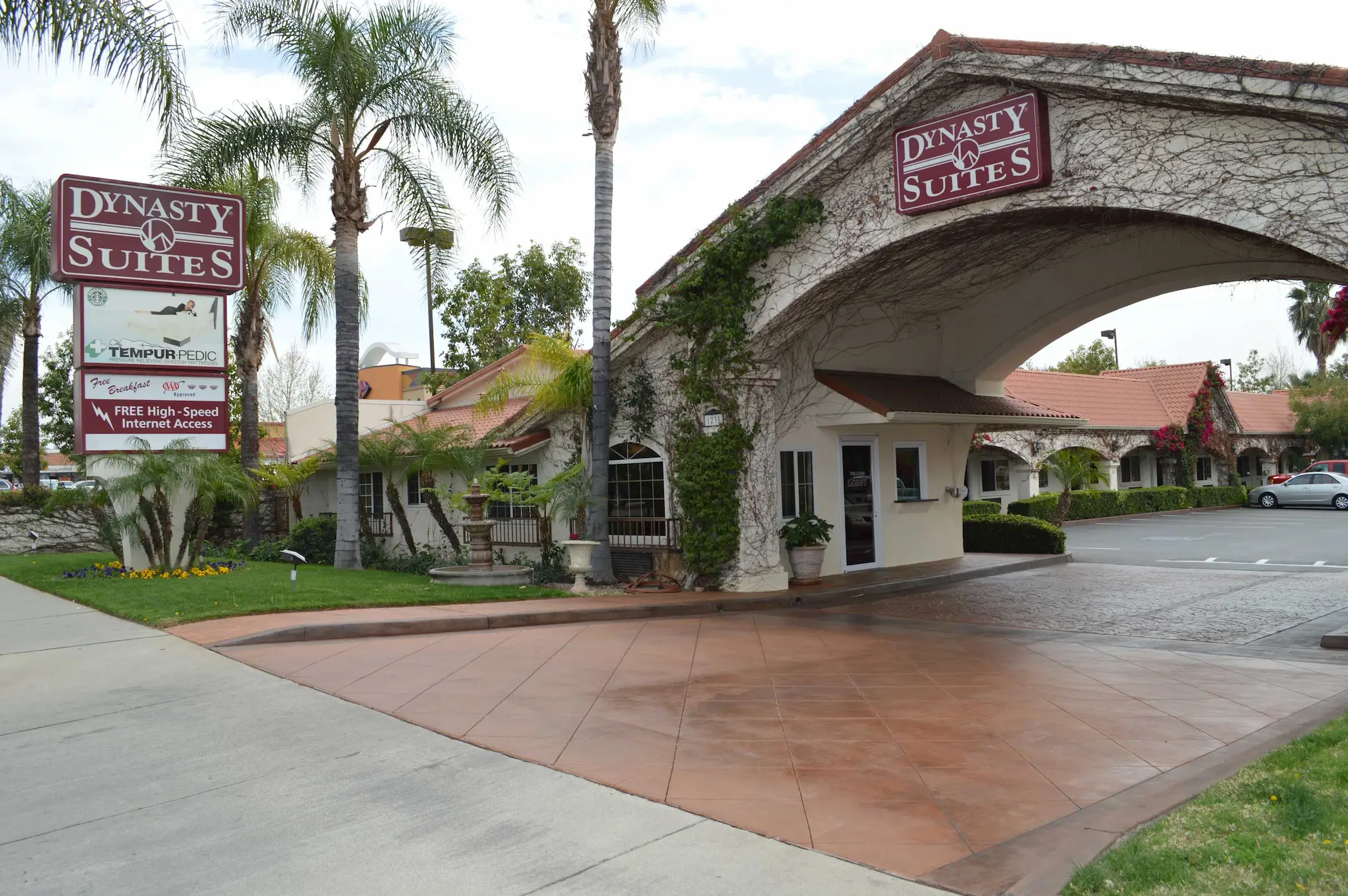 The entrance and palm-lined grounds of Dynasty Suites Redlands